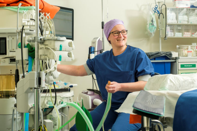 Anesthesia technician sitting in front of a medical device