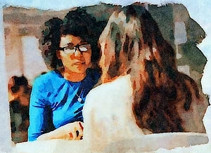 Two women sitting behind a table and talking with each other