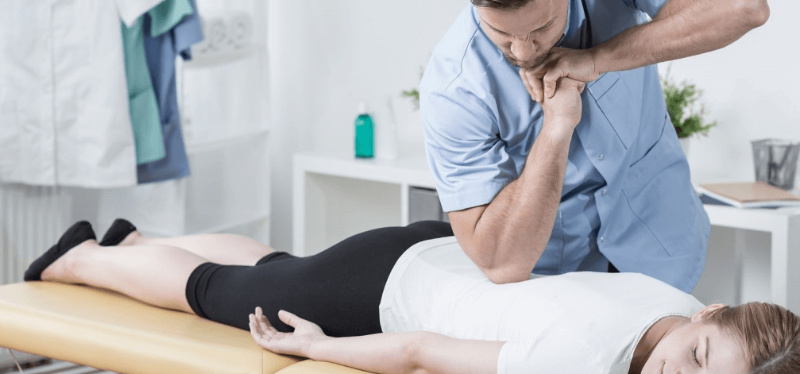 A chiropractor kneading patient's back muscles