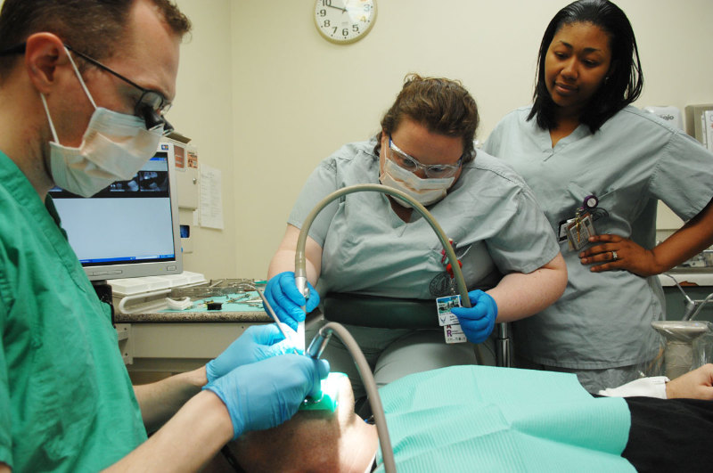 Two dental assistants assisting a dentist