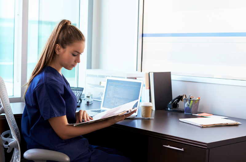 Medical biller/coder sitting behind a desk with a laptop