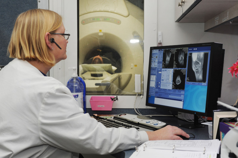 A female radiologic technologist operating a MRI scanner
