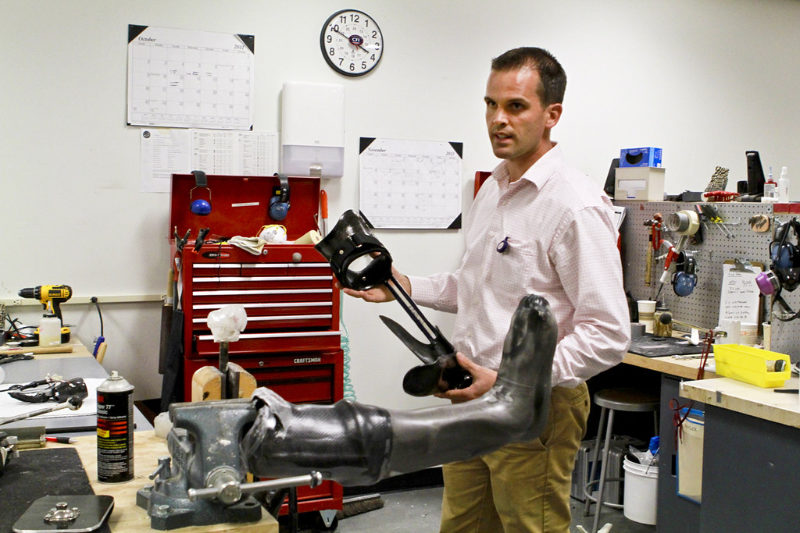 An orthotist in his workshop holding a prosthesis