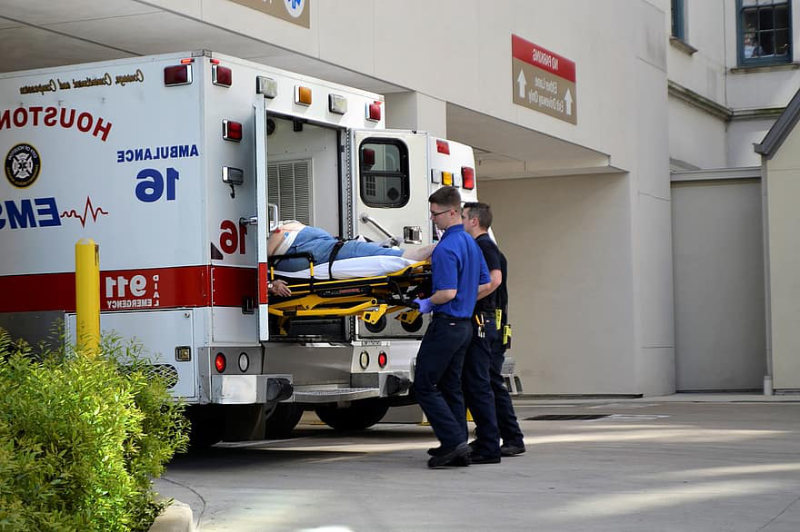 Two paramedics loading a patient on a stretcher into an ambulance coach