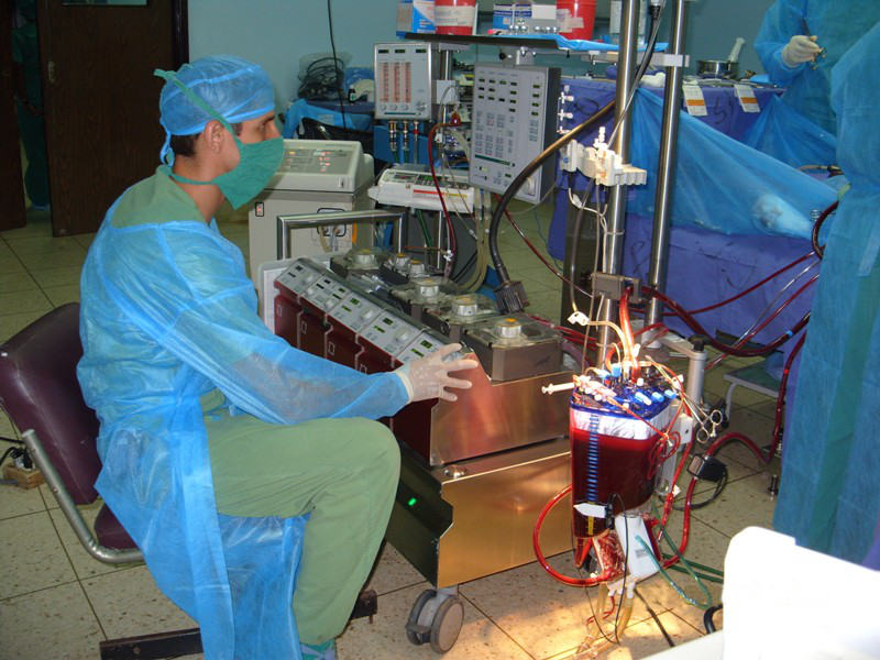 A male perfusionist operating a heart-lung machine during a surgeon