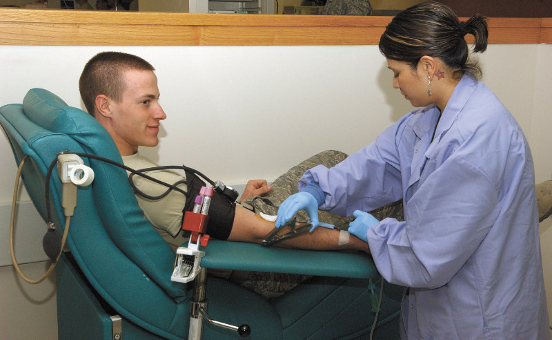 A female phlebotomist drawing blood from patient's arm