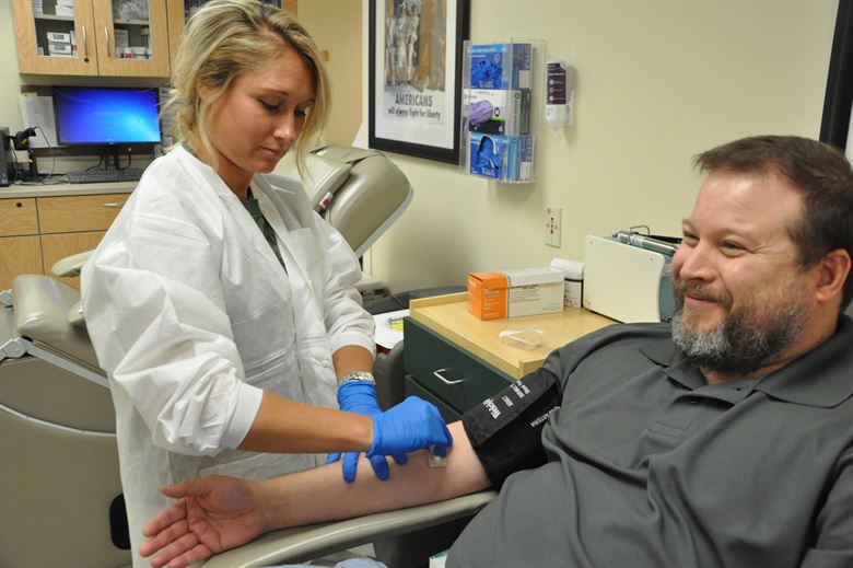 A phlebotomist drawing blood from a patient