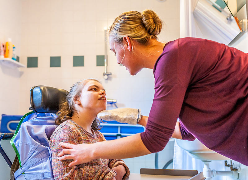 A female psychiatric aide talking with a cognitively disabled person in a wheelchair