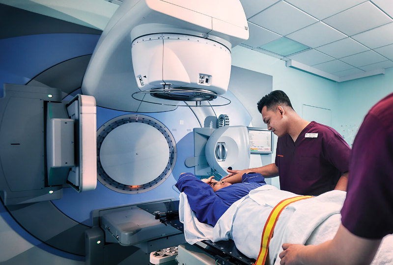 A male radiation therapist preparing a patient for a radiation treatment