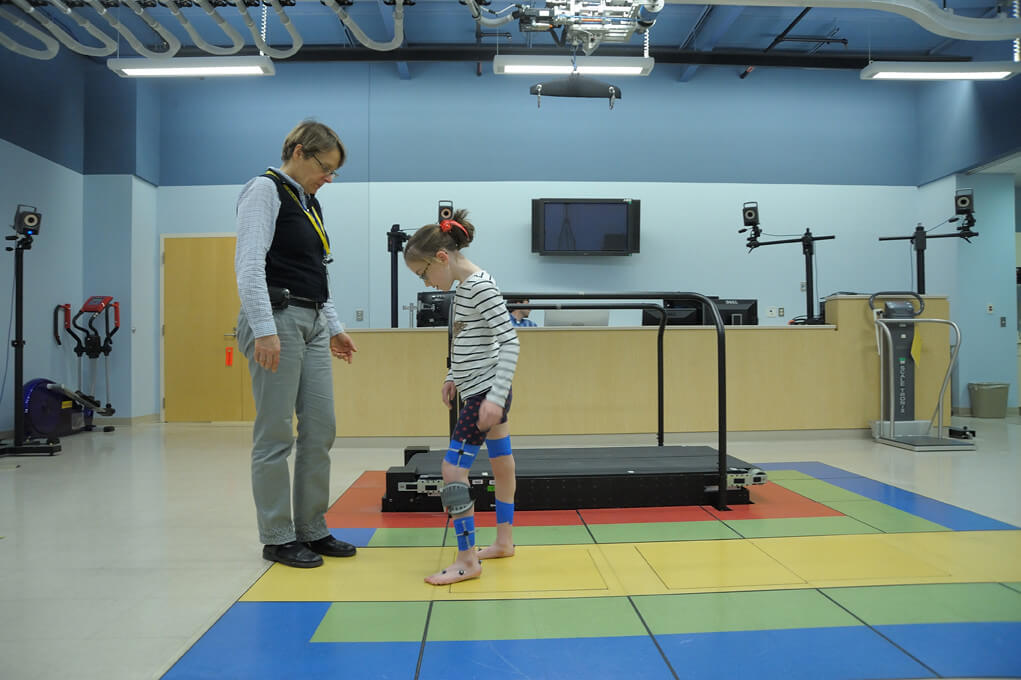 A recreational therapist overseeing a young girl with a prosthesis