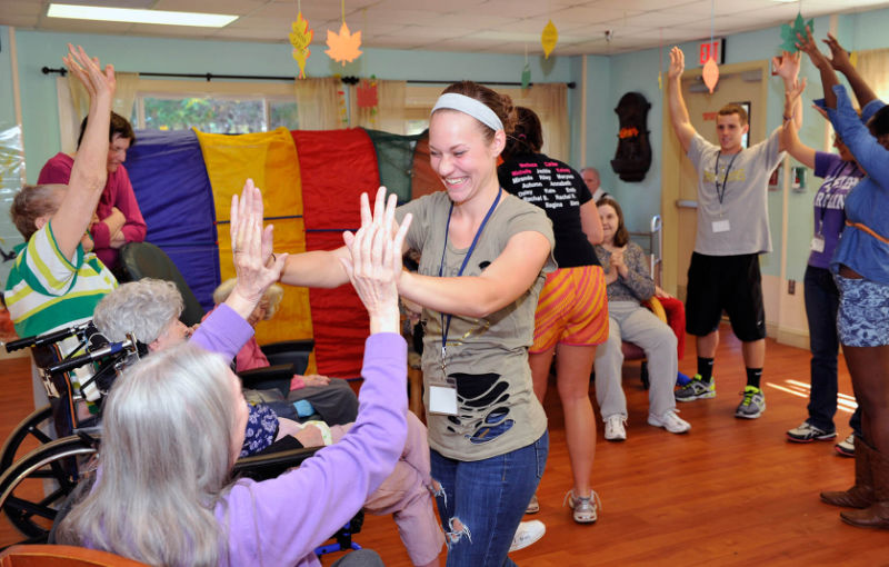 A recreational therapist entertaining an elderly person
