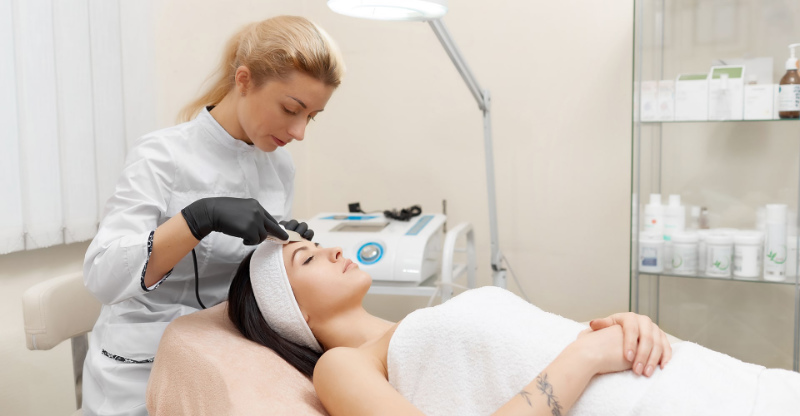 A female Esthetician/Skincare Specialist administering a facial skin treatment