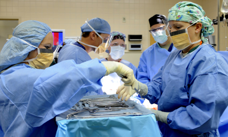 Surgical technologists handing over a surgical instrument